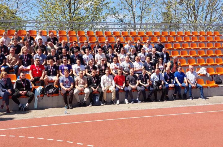 Tim sportske ekipe okupljen na stadionu tokom sunčanog dana.