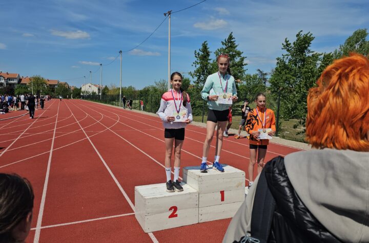Dvoje mladih atletičara na pobedničkom postolju tokom takmičenja na atletskom stadionu.
