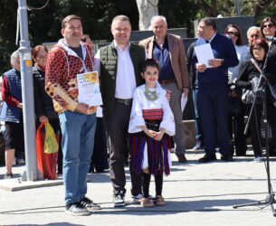 Grupa ljudi na javnoj manifestaciji u Požarevcu, uključujući devojku u tradicionalnoj nošnji.