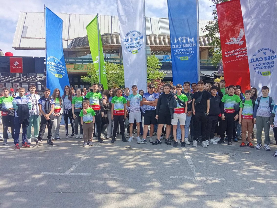Ekskurzija učenika ispred zgrade sa zastavama i školskim uniformama.