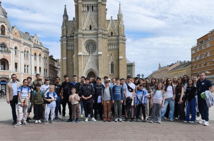 Vesela grupa učenika ispred crkve u Požarevcu, spremni za školsku ekskurziju ili izlet.