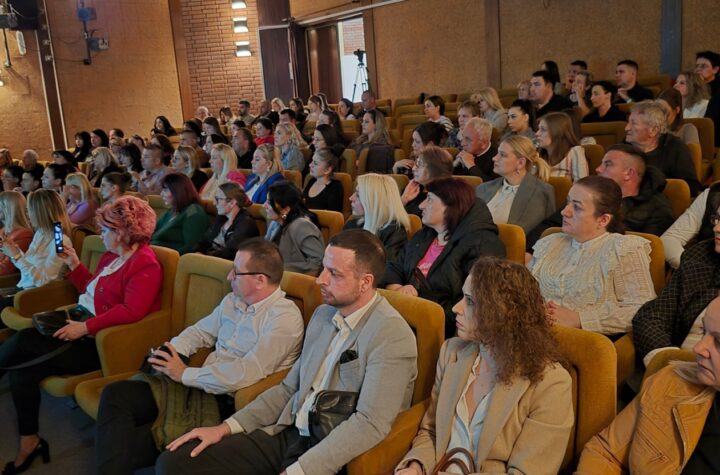 Učesnici konferencije pažljivo slušaju prezentaciju u velikoj sali.