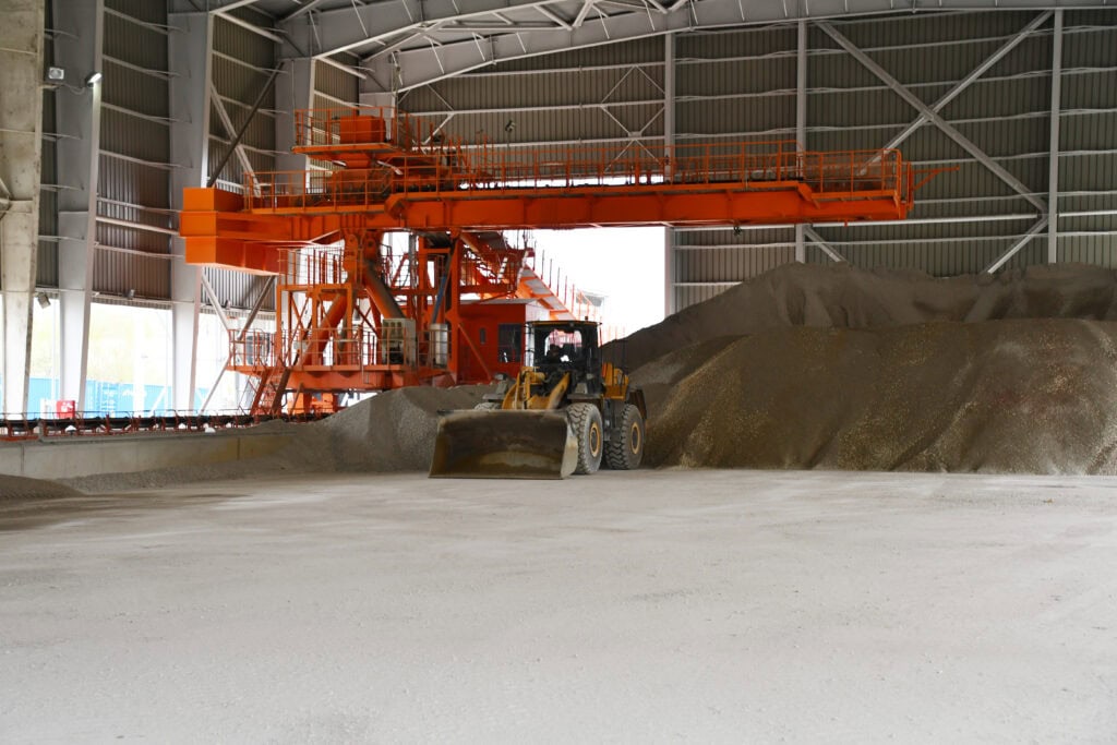 Industrijska hala sa mašinom za utovar mineralnih sirovina u skladištu.