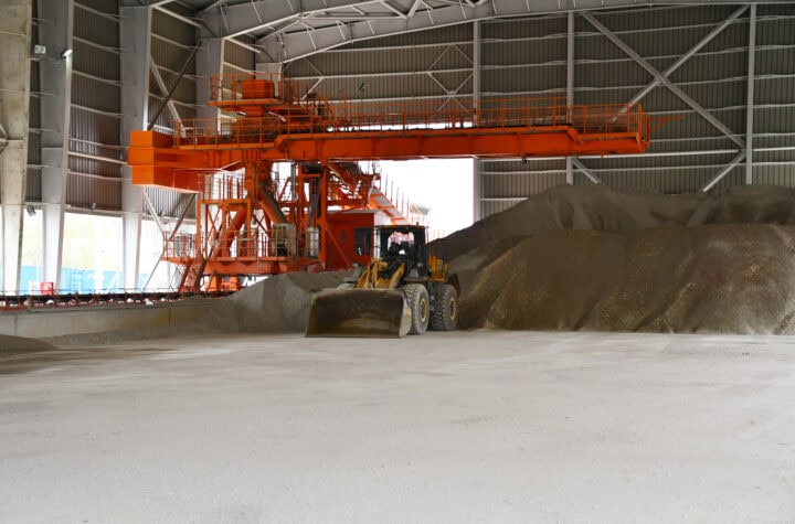 Industrijska hala sa mašinom za utovar mineralnih sirovina u skladištu.
