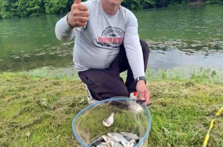Čovek sa ribarskom mrežom punom riba pored reke Požarevac.