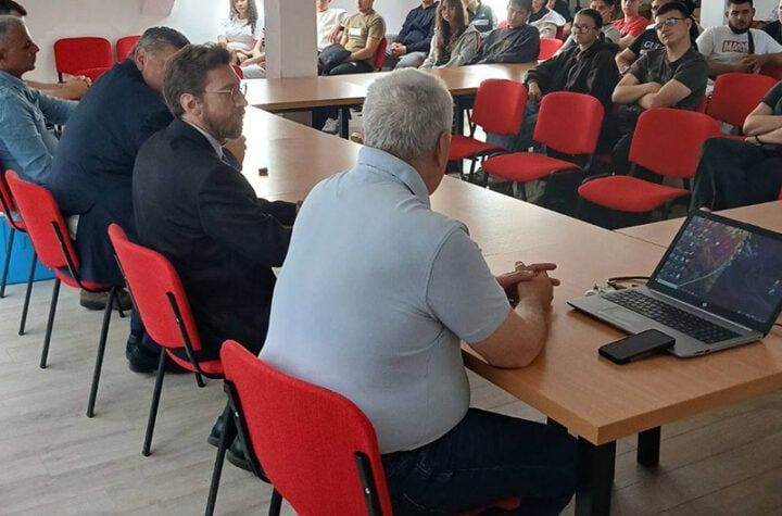 Učesници sastanka u konferencijskoj sali, fokusirani na diskusiju i prezentaciju.