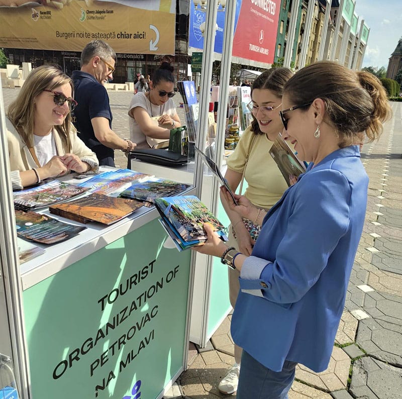 Grupa ljudi na štandu Turističke organizacije Požarevac, razgledaju brošure i informišu se o lokalni.