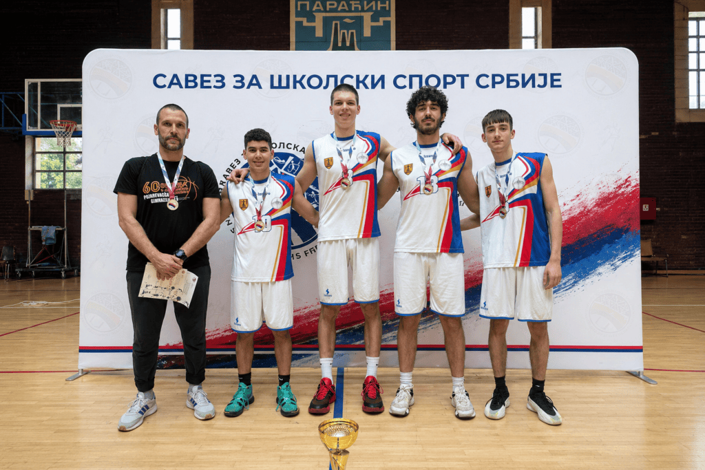 Sastav košarkaškog tima sa trenerom na takmičenju u zatvorenom sportskom centru.