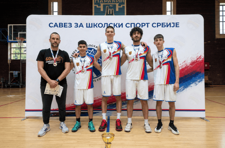 Sastav košarkaškog tima sa trenerom na takmičenju u zatvorenom sportskom centru.