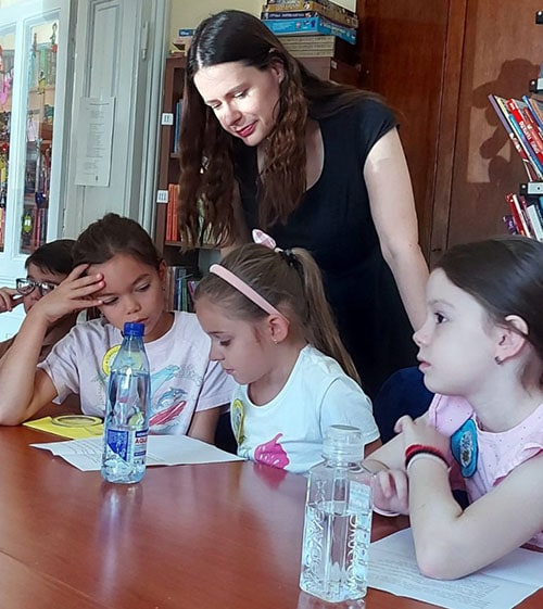 Deca na radionici uz učiteljicu, čitaju i crtaju.