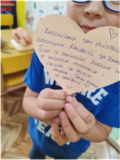 Dete drži srce s porukom podrške i ljubavi.